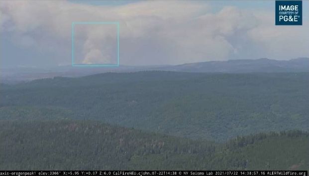 Wildfire alert camera view of a smoke plume over a forested ridge